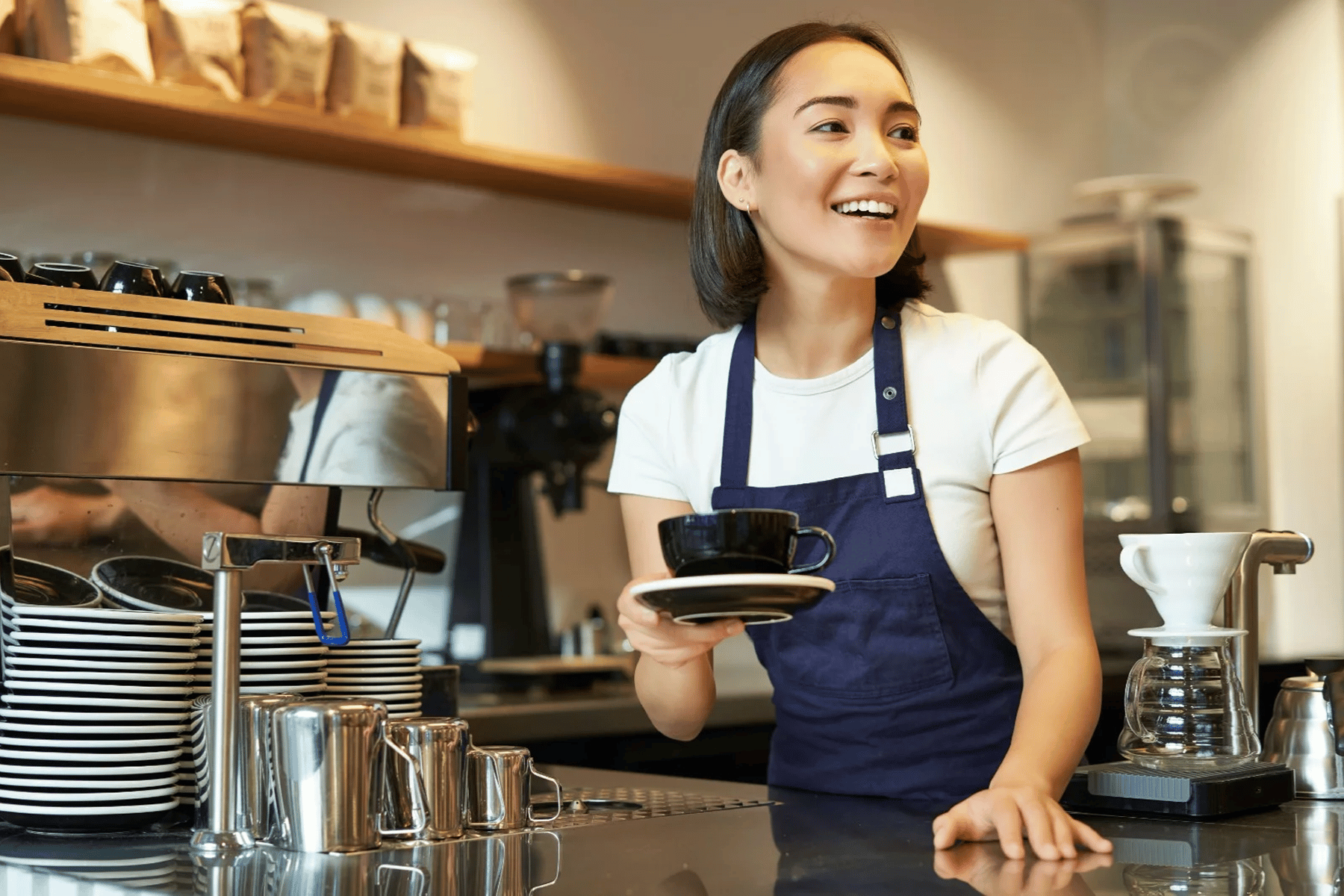 Barista sonriente entregando una taza de café en una cafetería moderna