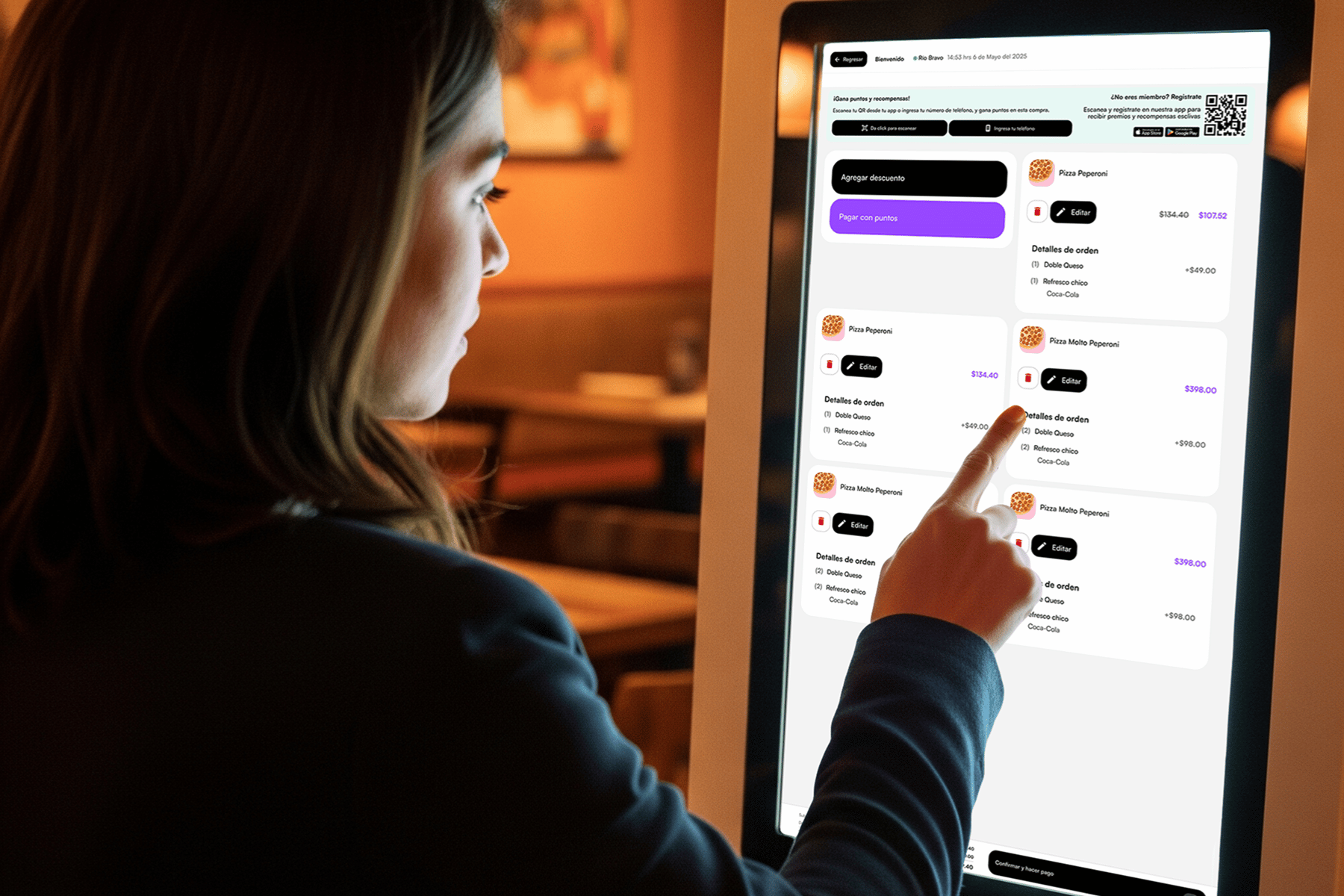 Mujer usando un kiosco digital para pagar su orden con puntos en un restaurante