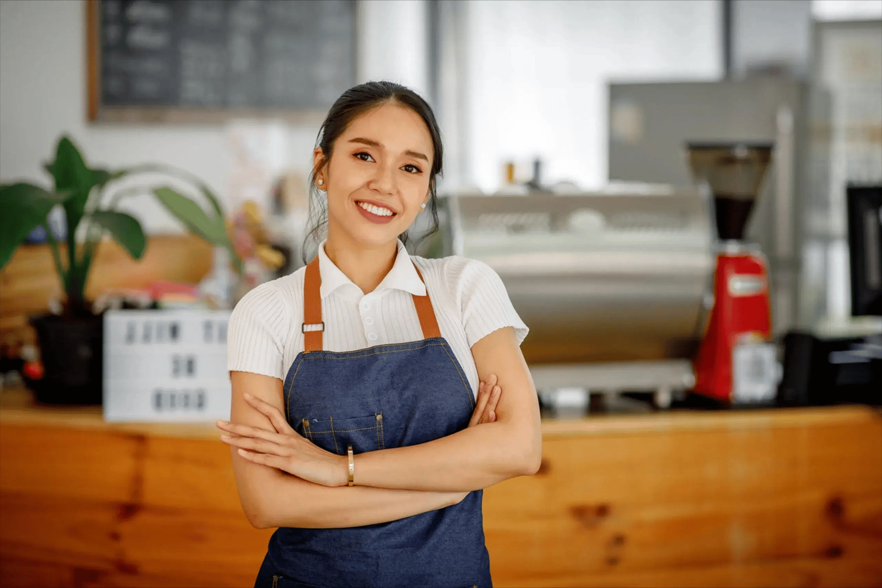 Dueña de cafetería con actitud positiva, brazos cruzados, sonriendo en su negocio