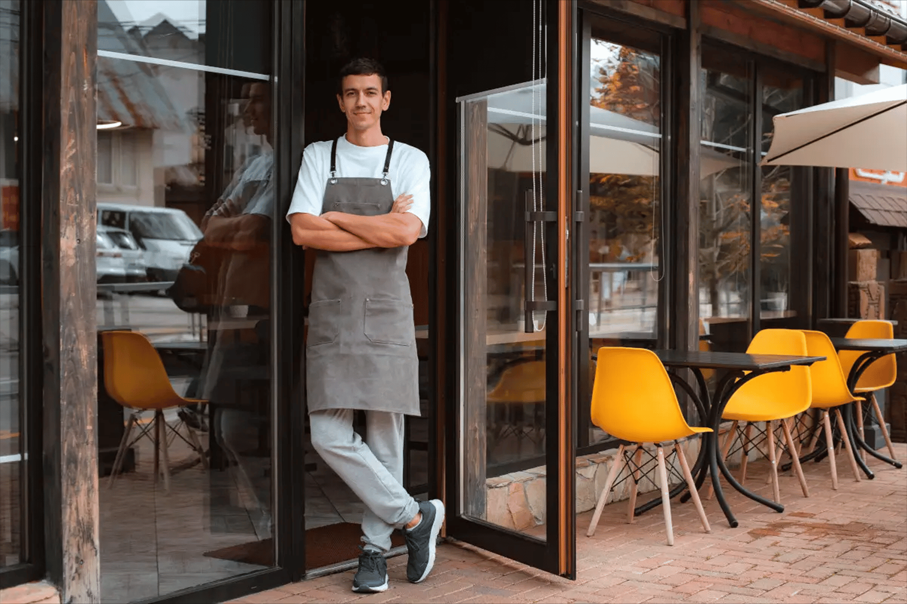 Dueño de cafetería sonriente de pie en la entrada del local