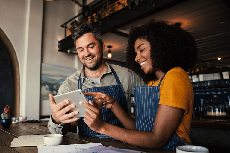 Dos personas con delantal usando una tableta para gestionar su restaurante