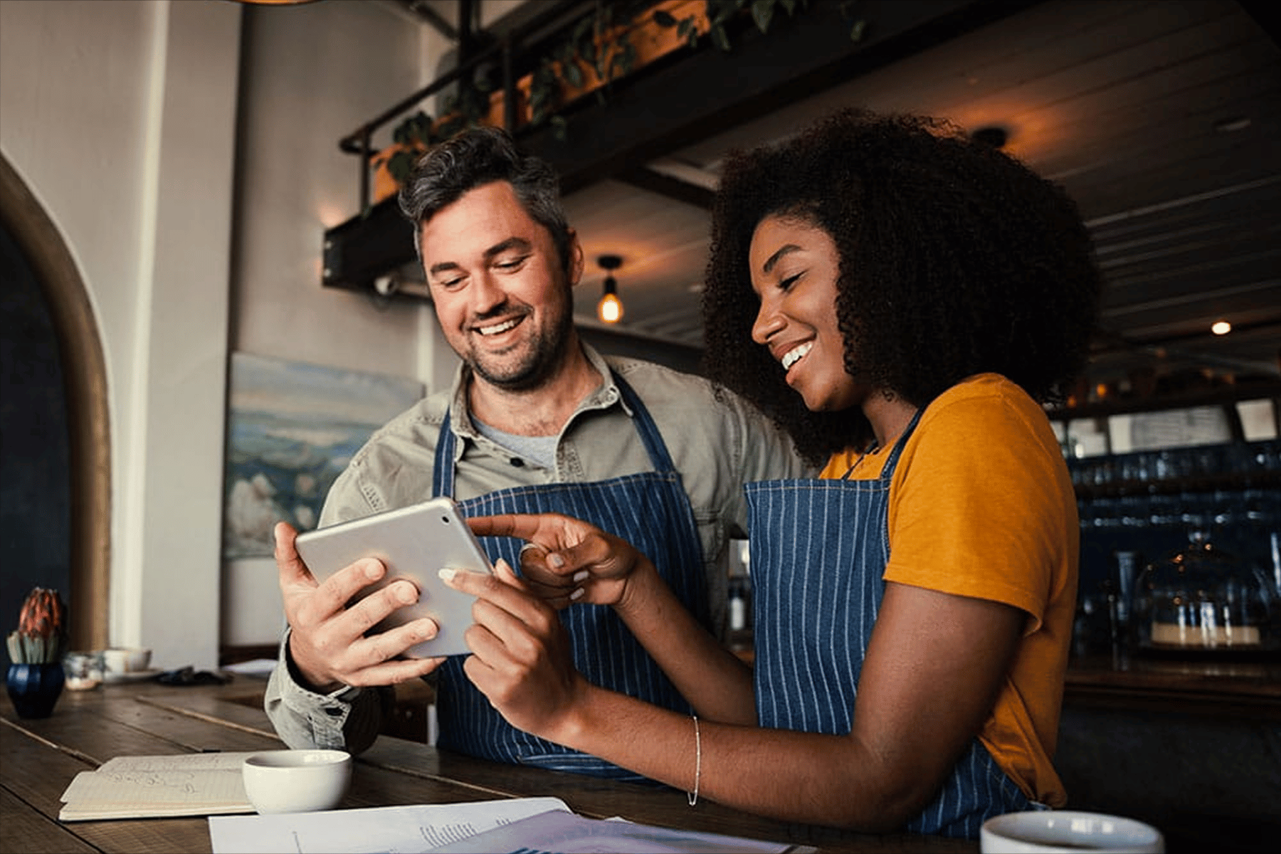Dos personas con delantal usando una tableta para gestionar su restaurante